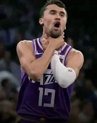 A man in a purple jersey is holding a basketball ball.