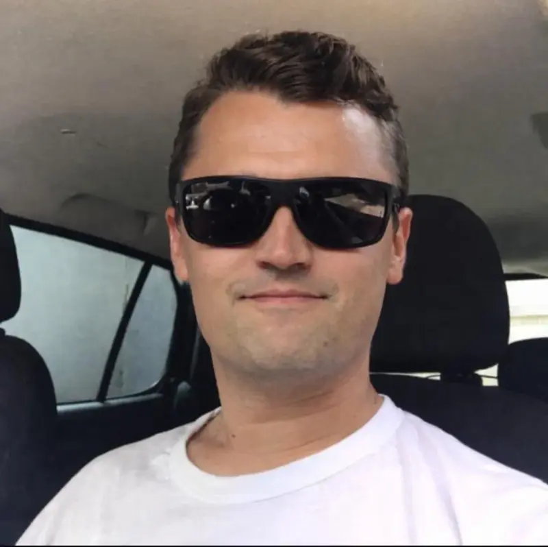 A man in sunglasses is sitting in the back seat of a car.