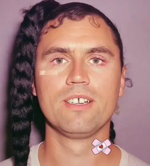 A man with long hair and a pink bow on his head.