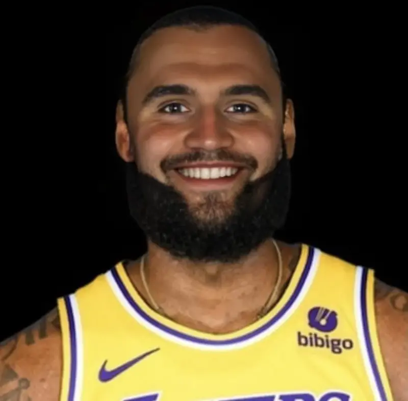 A man with a beard and tattoos smiles at the camera.