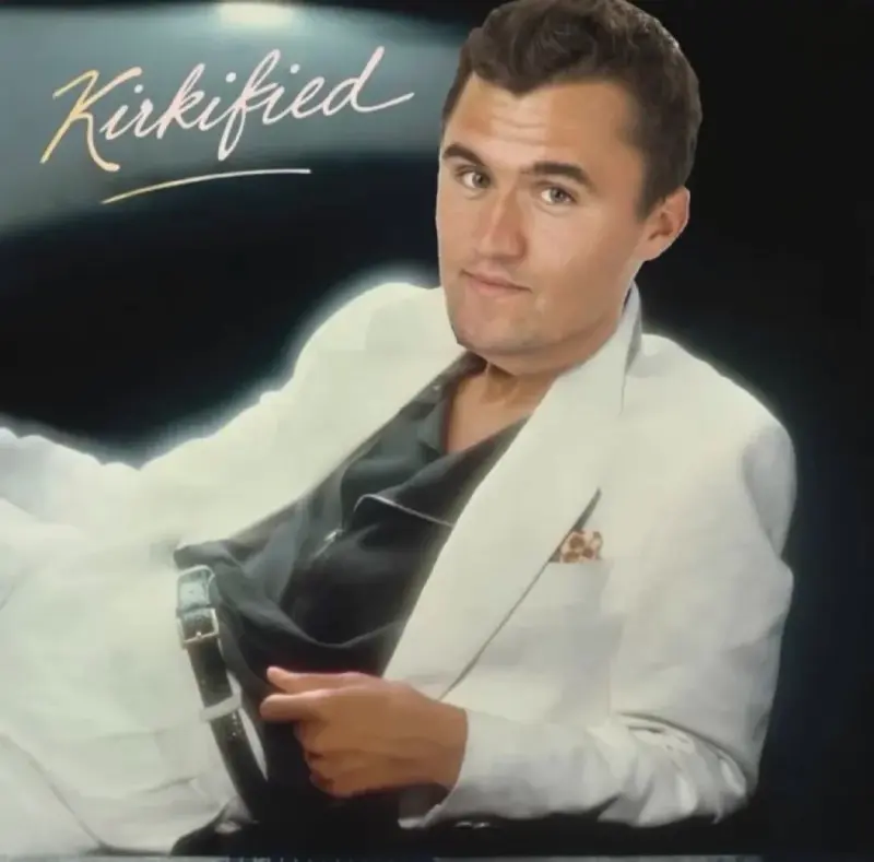A man in a white suit and tie holding a cell.