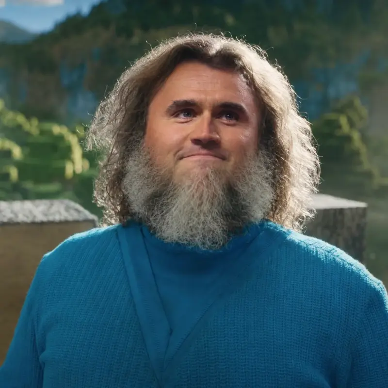 A man with long hair and beards stands in front of a mountain.