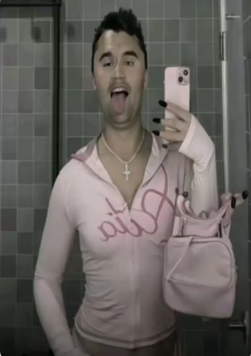 A man in a pink shirt is taking a selfie.
