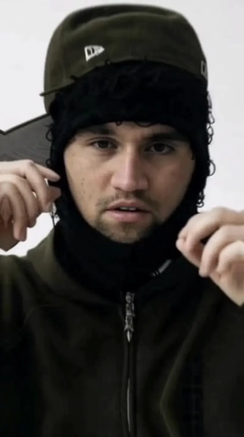 A man in a green jacket and black hat.