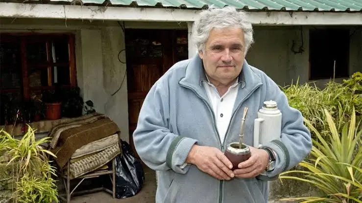 A man holding a can of paint in front of a house.