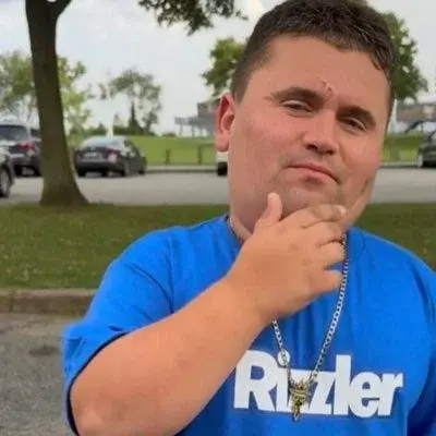 A man in a blue shirt is sitting on a bench.