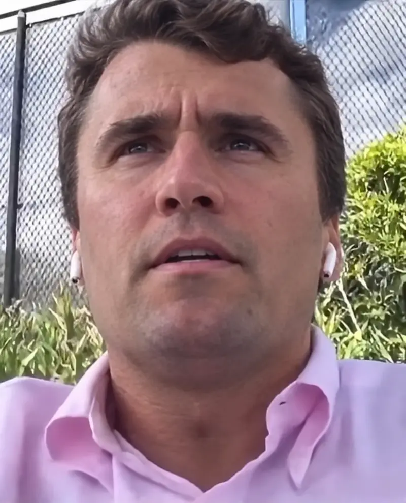 A man in a pink shirt is looking up at the camera.