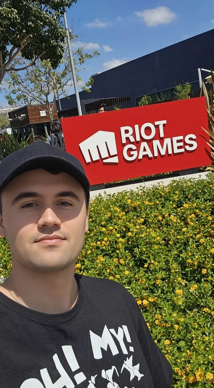 A man in a black shirt and hat standing in front of a sign.