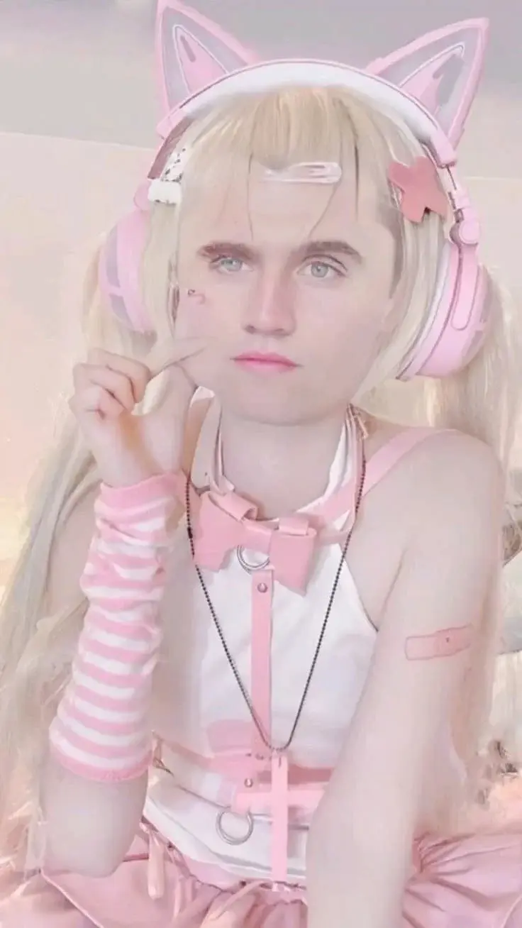 A girl in pink and white is sitting on a bed.