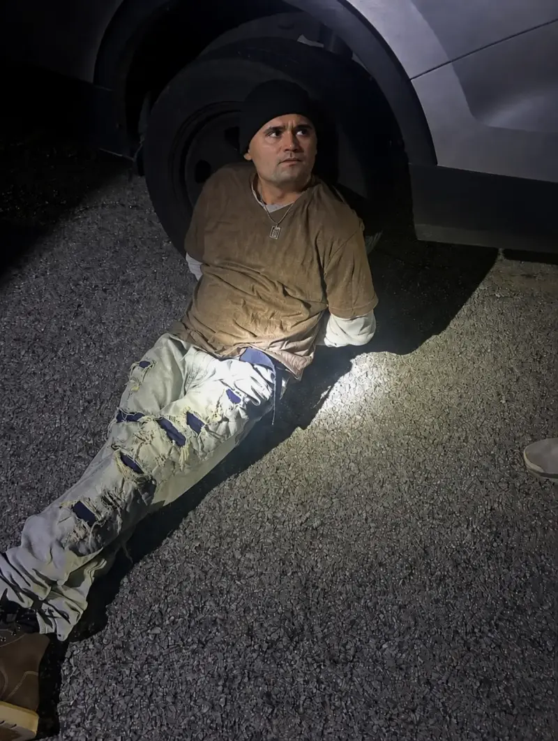 A man sitting on the ground next to a car.