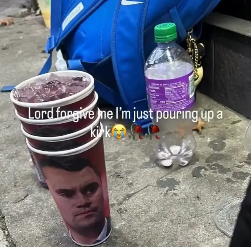 A person is walking down the sidewalk with a cup.