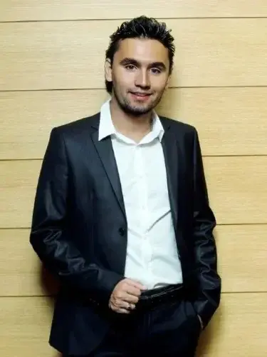 A man in a suit standing next to a wall.