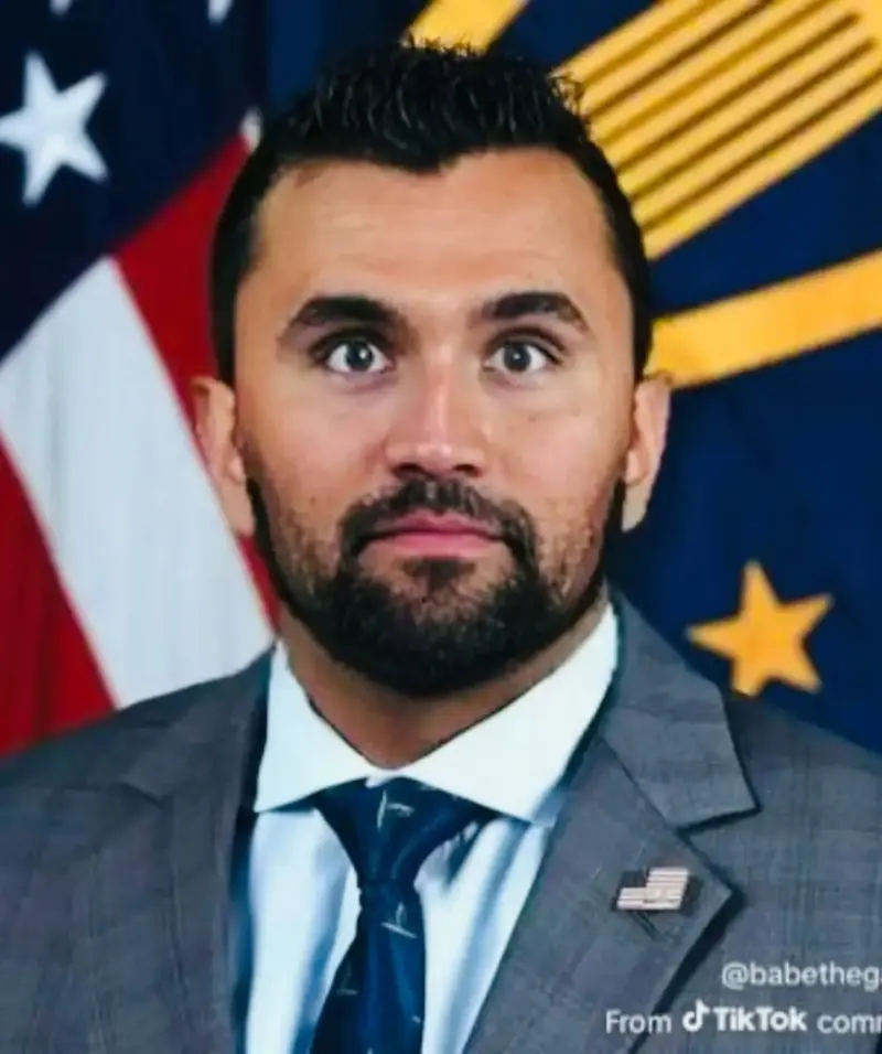 A man in a suit and tie standing in front of an american flag.