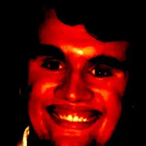 A man smiling with a red light on his face.