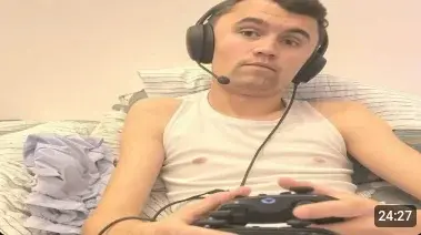 A man sitting on a bed holding a game controller.