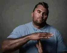 A man in a blue shirt is holding his hands out.