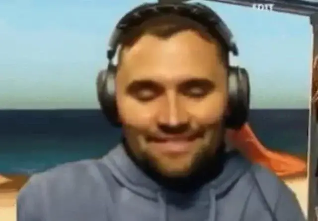 A man in headphones is sitting on a beach.