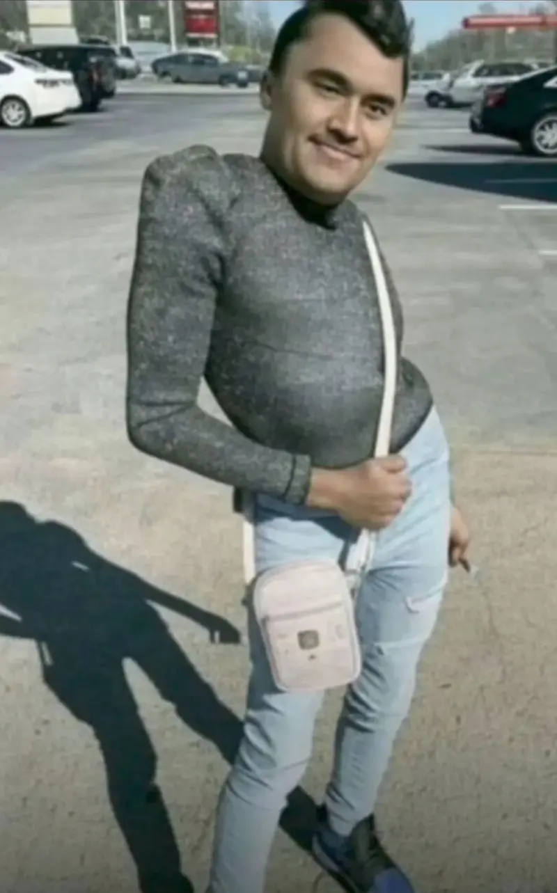 Hay un hombre con un jersey gris y vaqueros de pie en el aparcamiento.
