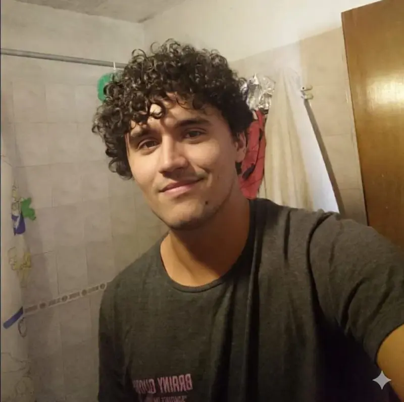 A man with curly hair is taking a selfie.