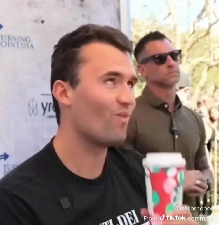 A man in a black shirt is talking to a reporter.