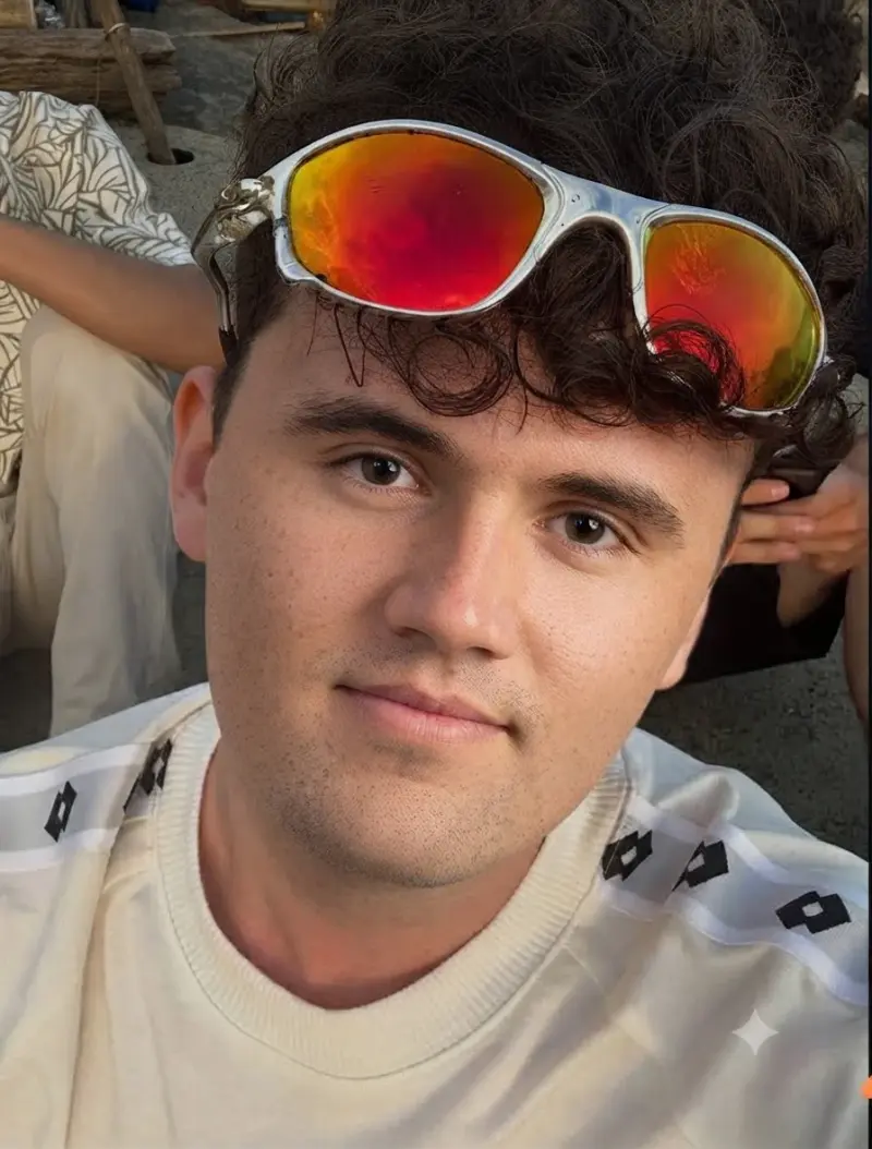 A man wearing sunglasses and a white shirt.